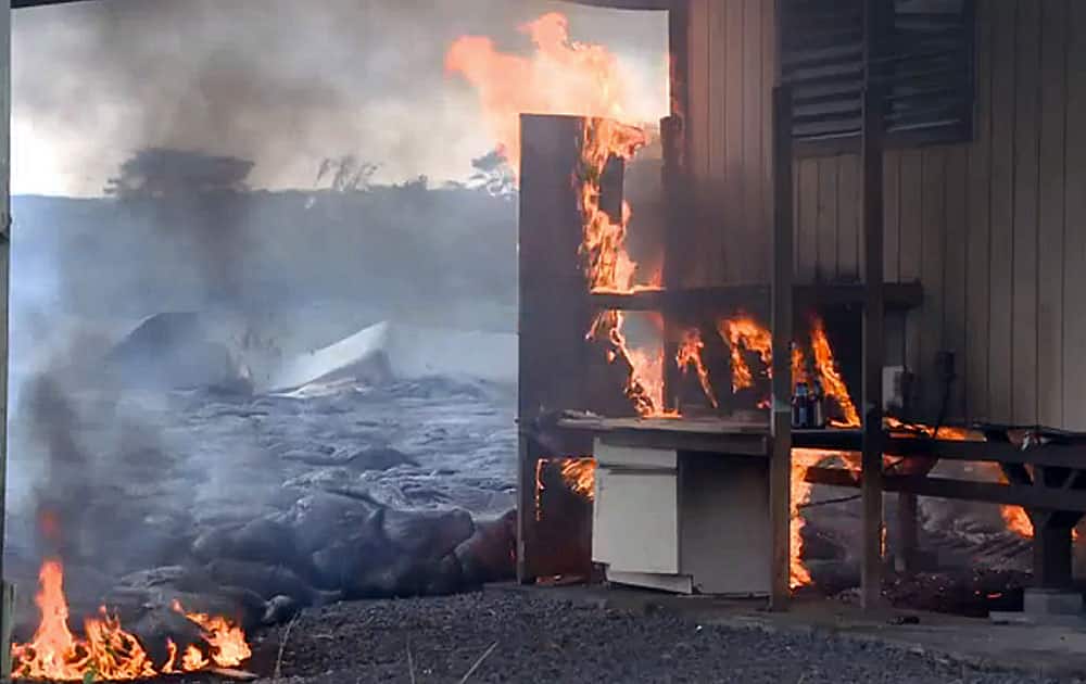In this image made from video provided by the County of Hawaii, lava flow from the Kilauea Volcano burns a residential structure, in Pahoa, Hawaii.