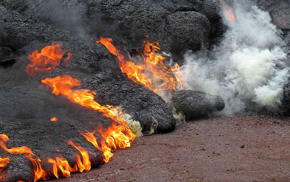 This photo provided by the US Geological Survey shows the lava flow from the Kilauea Volcano that began on June 27 as it burns along Cemetery Road and Apa?a Street near the town of Pahoa on the Big Island of Hawaii.