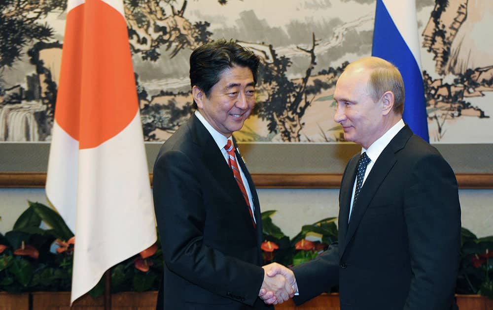 Russian President Vladimir Putin, right, shakes hands with Japanese Prime Minister Shinzo Abe at sidewalks of the Asia-Pacific Economic Cooperation (APEC) forum in Beijing. 