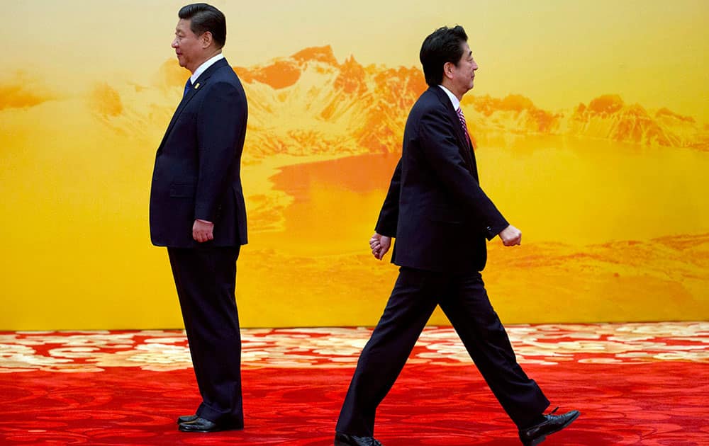 Japan's Prime Minister Shinzo Abe, right, walks past Chinese President Xi Jinping during a welcome ceremony for the Asia-Pacific Economic Cooperation (APEC) summit at the International Convention Center in Yanqi Lake, Beijing.