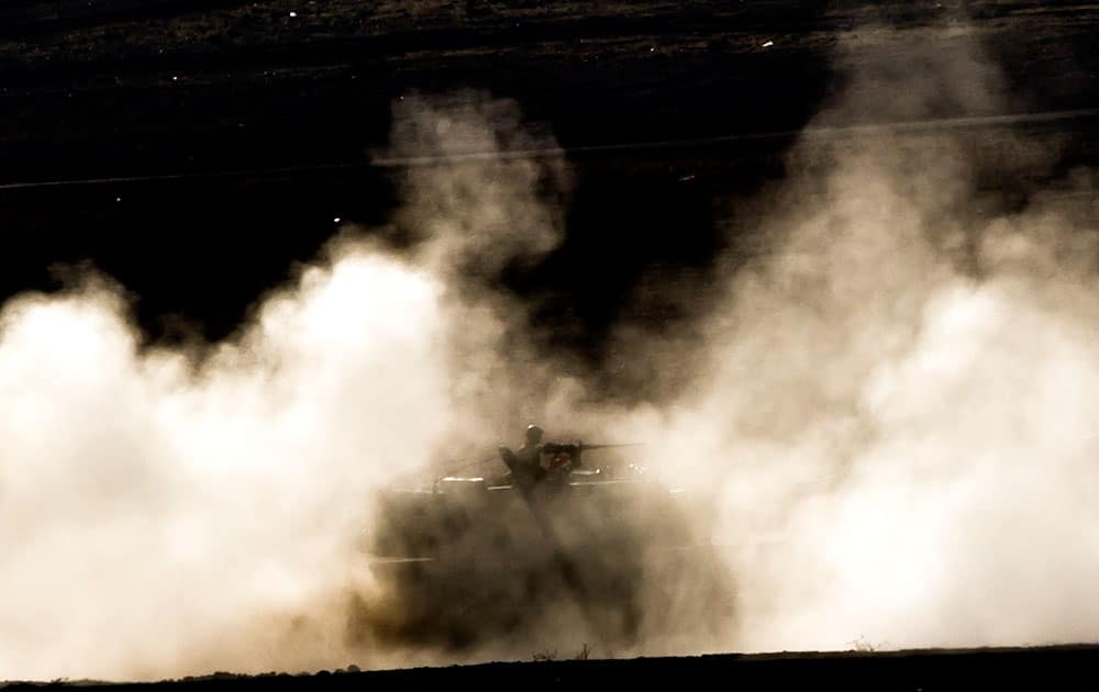 A Turkish military mobile artillery vehicle is engulfed by dust as it maneuvers on a hill overlooking the Syrian city of Kobani, outside Suruc, on the Turkey-Syria border.