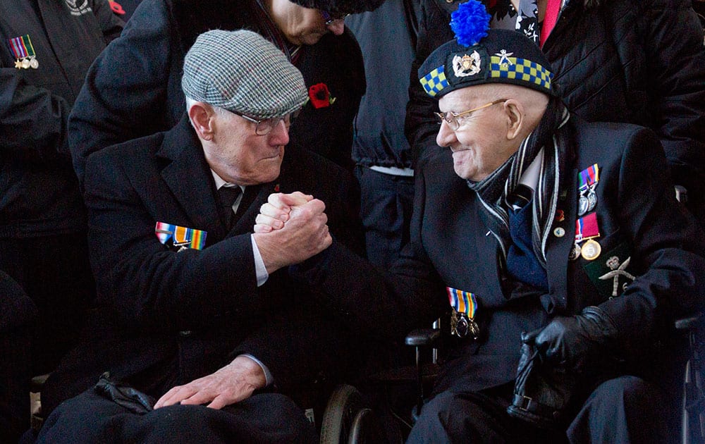 British World War II veterans David Ovenstone, right, and Leslie Potter hold hands during an Armistice Day ceremony at the Menin Gate in Ypres, Belgium.