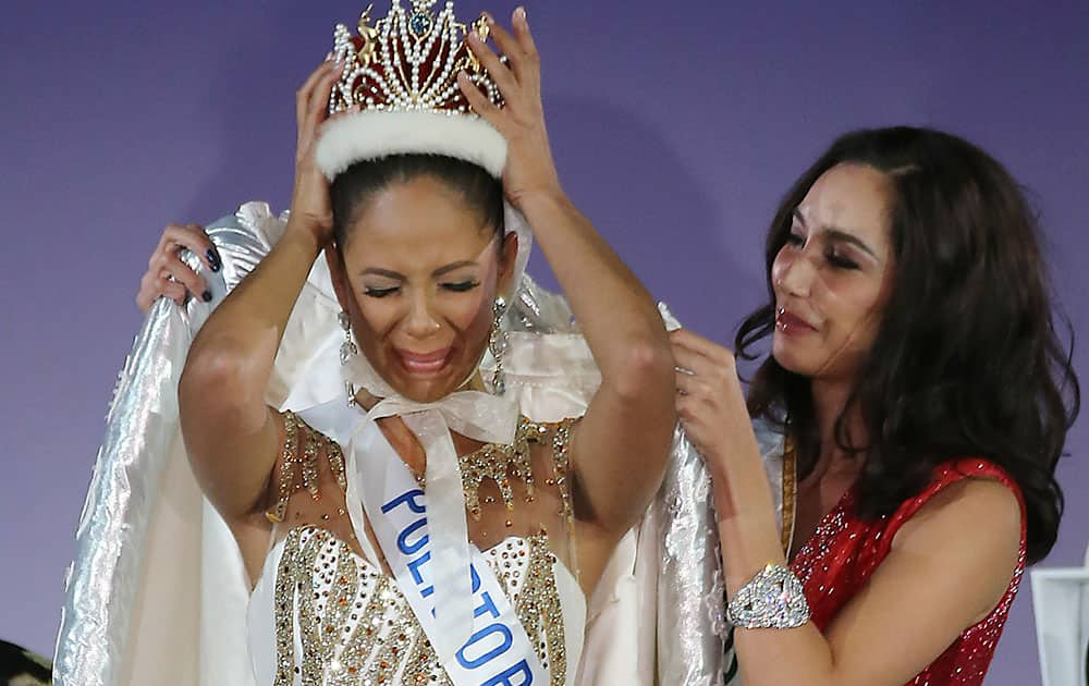 Newly-crowned Miss International Valerie Hernandez Matias, left, of Puerto Rico cries as the winner of Miss International 2013 Bea Rose Santiago, right, of the Philippines helps her queen gown during the final of Miss International Beauty Pageant in Tokyo.