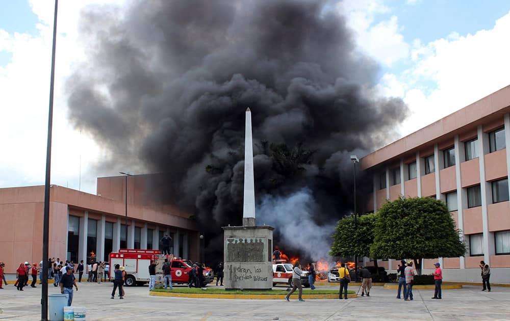 Firefighters arrive to try to extinguish several burning vehicles in front of the state congress building after protesting teachers torched them in the state capital city of Chilpancingo, Mexico.