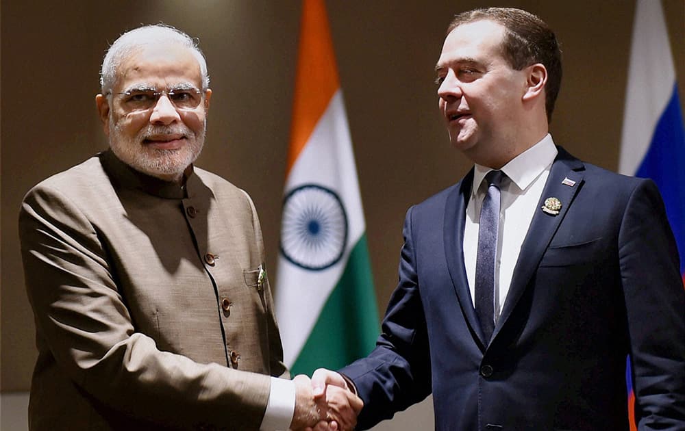 Prime Minister Narendra Modi shakes hands with his Russian counterpart Dmitry Medvedev at a meeting.
