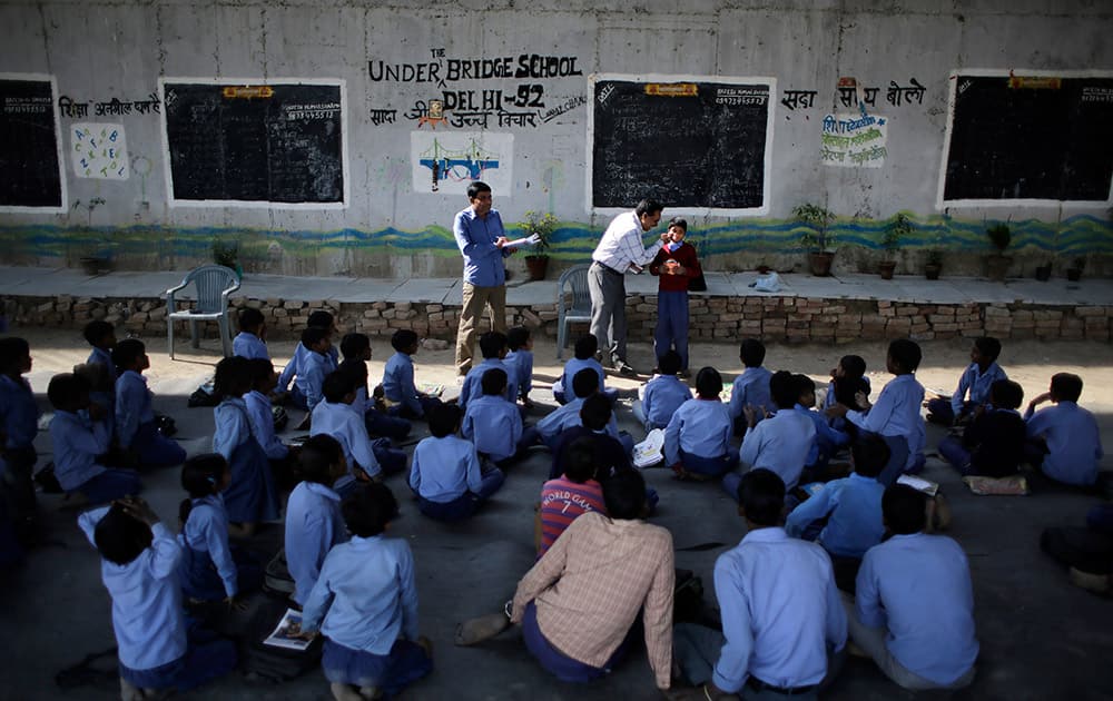 Rajesh Kumar, teacher and founder of a free school for slum children run under a metro bridge, distributes solar lanterns donated by a US donor in New Delhi.