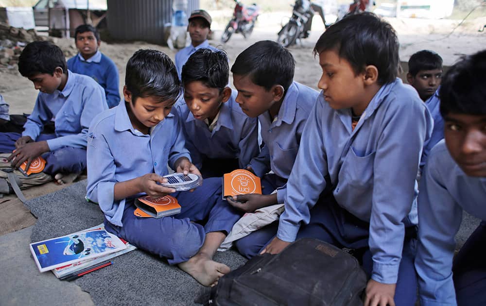Students of a free school run under a mass transit bridge for impoverished children look at solar lanterns donated by a US donor in New Delhi.