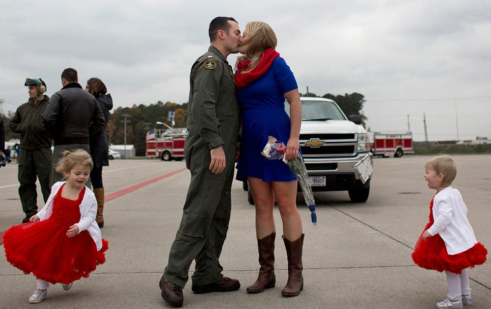 Lt. Doug DeVuono, kisses his wife, Kim, as their two daughters, Leah, 3, and Ava, 18-months, run around the them on his arrival to Naval Air Station Oceana in Virginia Beach, Va. 