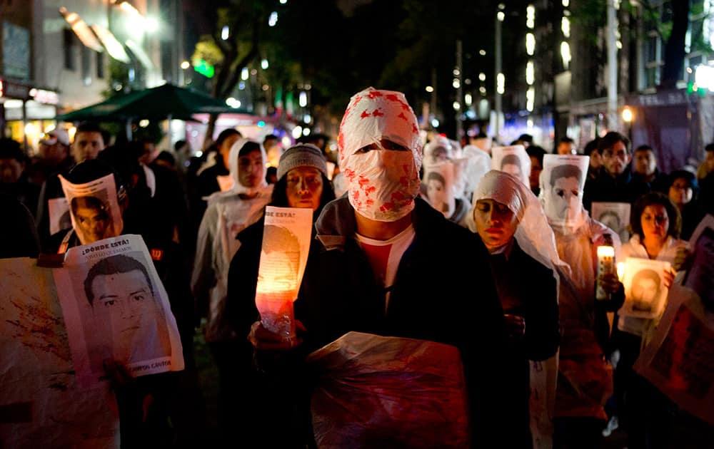 Demonstrators hold candles and images of some of the 43 students who were disappeared, in Mexico City. The 43 teachers-school students disappeared at the hands of a city police force on Sept. 26 in the town of Iguala.