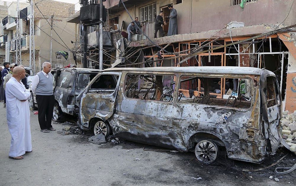 Civilians inspect the site of Friday's car bomb in Baghdad, Iraq. The nighttime blast in the Gorayaat area was the largest of four bombings in and around the city on Friday, mostly targeting Shiite areas.