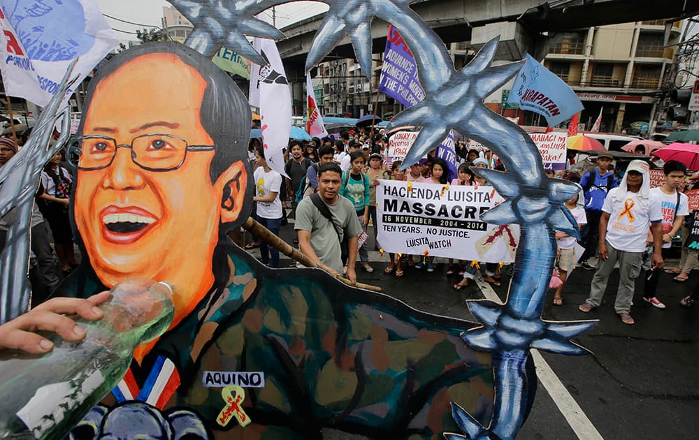 Protesters prepare to burn a cutout of Philippine President Benigno Aquino III during a rally near the Presidential Palace in Manila, Philippines, to mark the 10th anniversary of the killing of seven farmers and supporters at the vast sugarcane plantation owned by the family of Corazon Aquino, the late mother of the President.