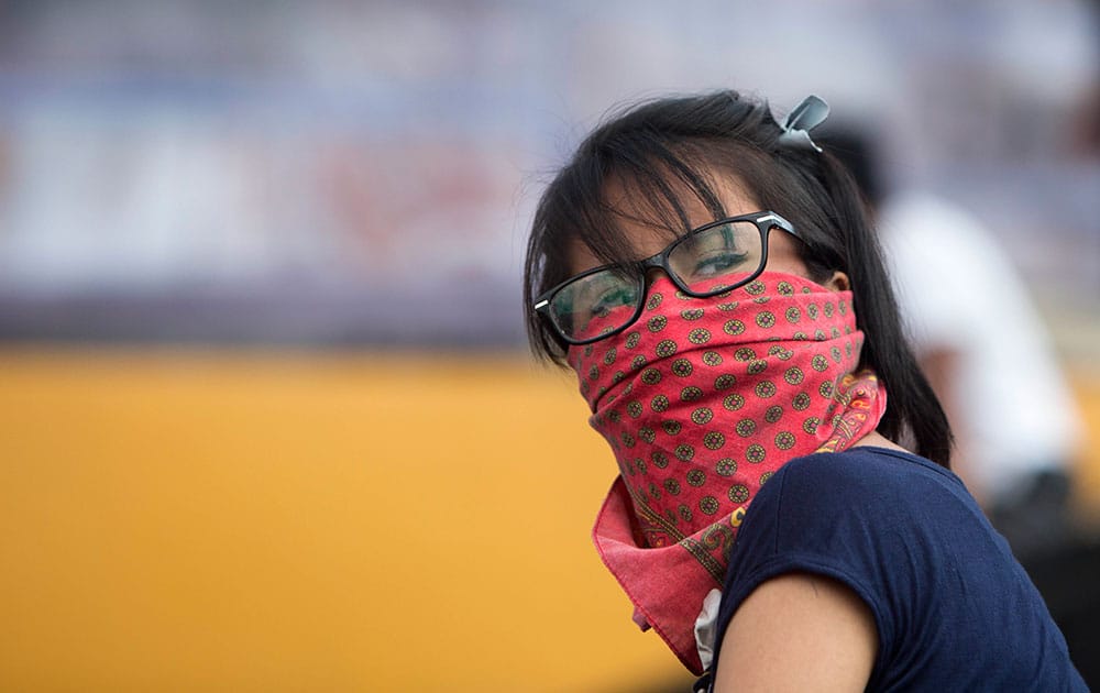 A student with her face covered looks over her shoulder as she marches inside Mexico's National University, UNAM, campus in Mexico City.