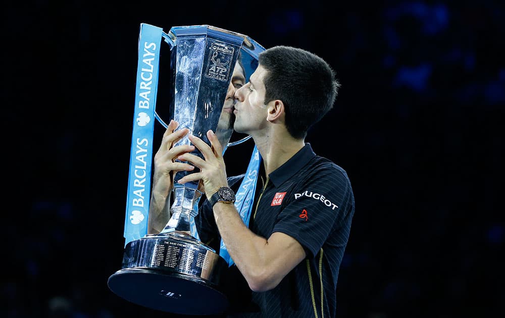 Serbia’s Novak Djokovic kisses the trophy of the ATP World Tour Finals tennis during an improvised presentation ceremony after a walkover due to injury of Switzerland’s Roger Federer in London. Federer withdrew due to an injured back.