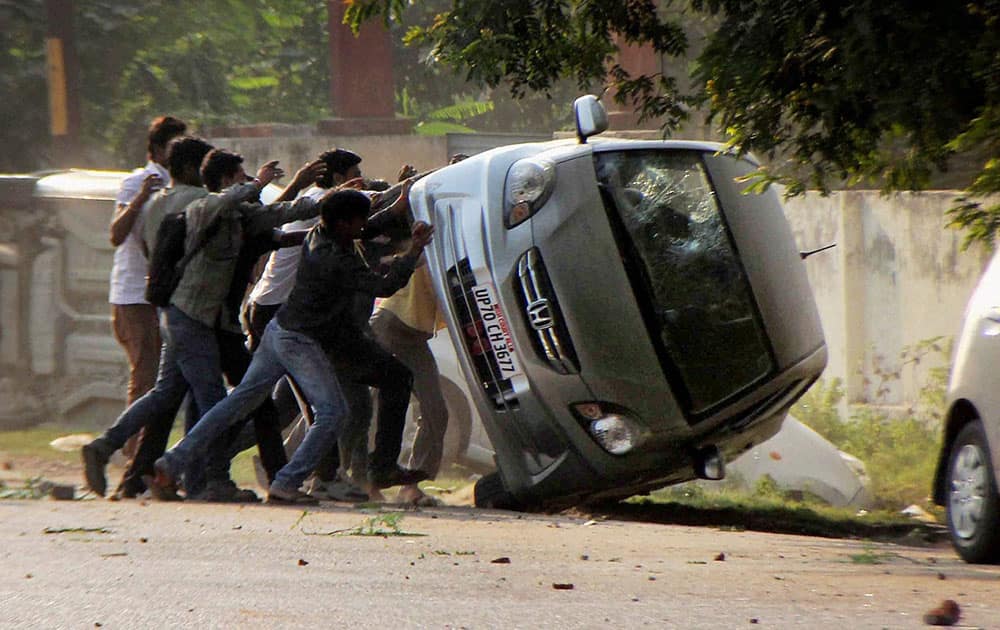 People overturn vehichle of a lawyer during a clash in Allahabad.