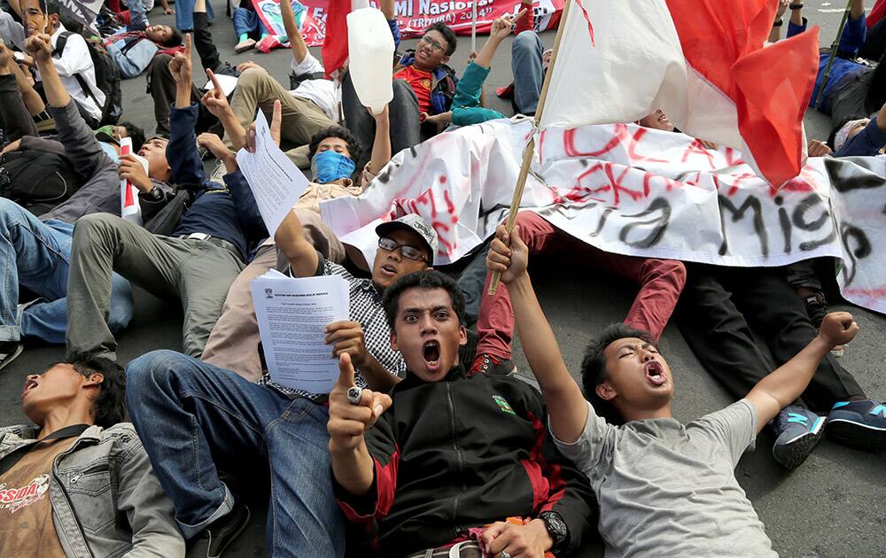 Students shout slogan as they lie down on the road during a protest against the fuel price hikes outside the presidential palace in Jakarta.