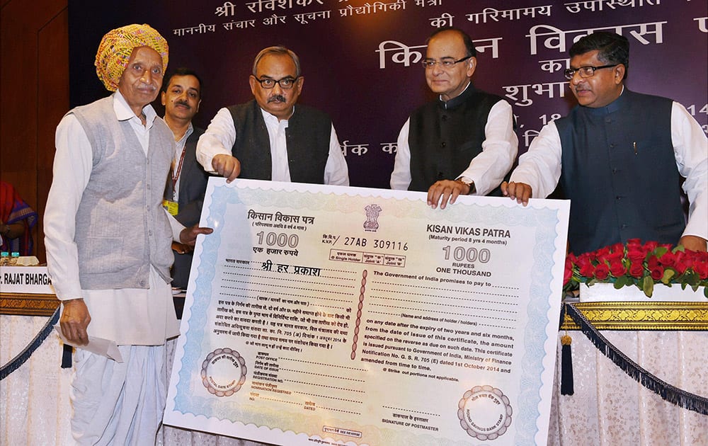 Union Finance Minsiter Arun Jaitley presents first KVP to Harprakash as Union Communications & Information Technology Minister Ravi Shankar Prasad looks on at the launch of the Kisan Vikas Patra (KVP) at a function in New Delhi.