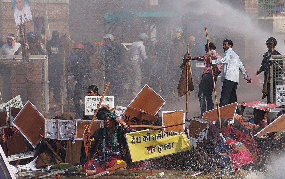 Supporters sit drenched in water as police use water cannon to disperse them, as they storm the ashram of controversial guru Sant Rampal, at Hisar in Haryana.