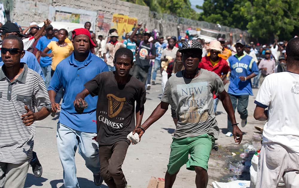 Anti-government protesters run with rocks during clashes with government supporters in Port-au-Prince, Haiti.