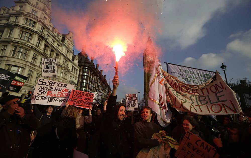 A protestor holds a flare as others parade with banners during a protest against university tuition fees in London.