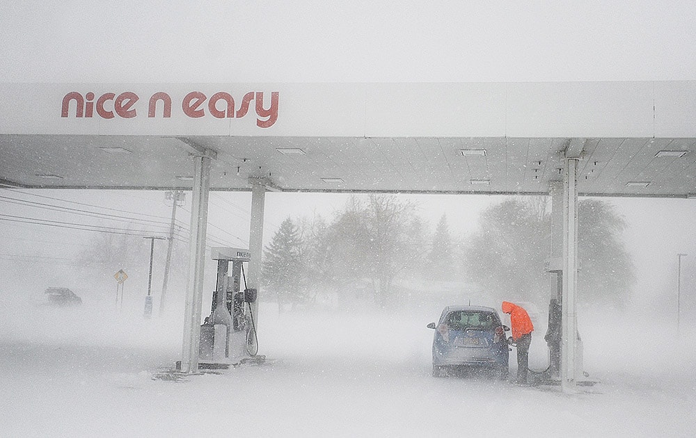 A man puts gas in his tank as snow falls at a gas station on New York State Route 12F near Brownville, N.Y. A ferocious lake-effect storm left the Buffalo area buried under 6 feet of snow, trapping people on highways and in homes, and another storm expected to drop 2 to 3 feet more was on its way.