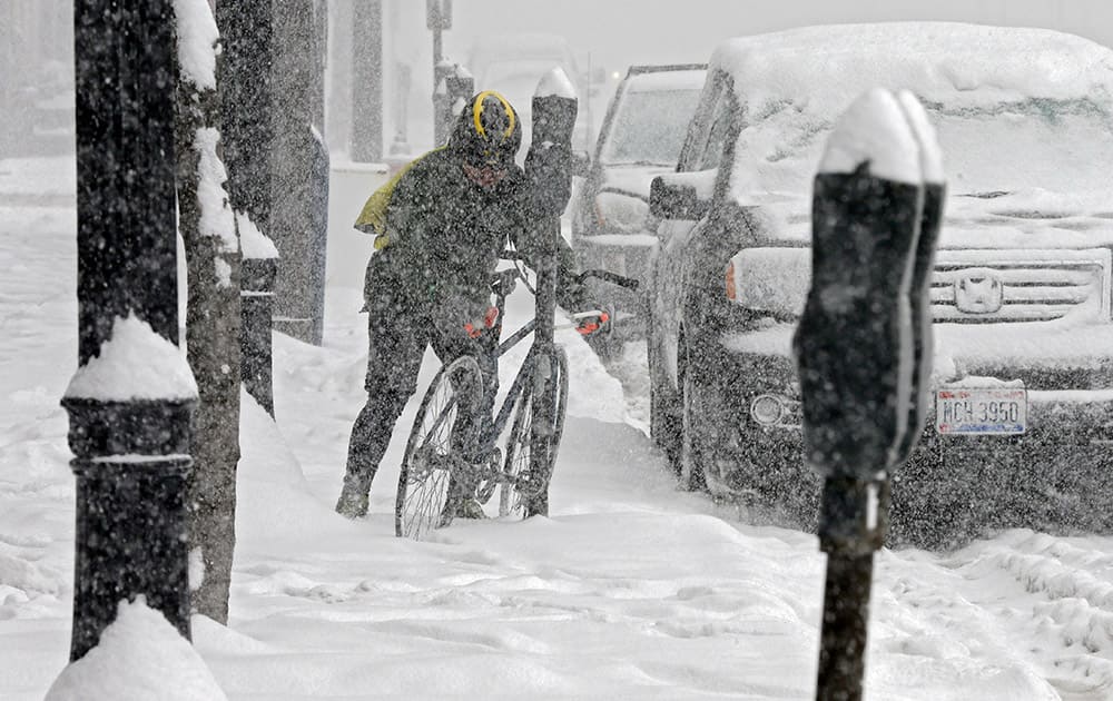 A bicycle messenger chains his bike to a snow-covered parking meter in downtown Cleveland.