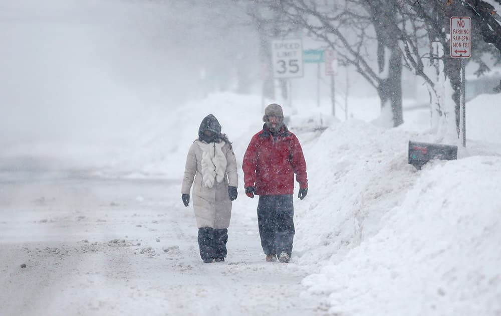 Pedestrians walk along a snow-covered street, in Lancaster, New York.