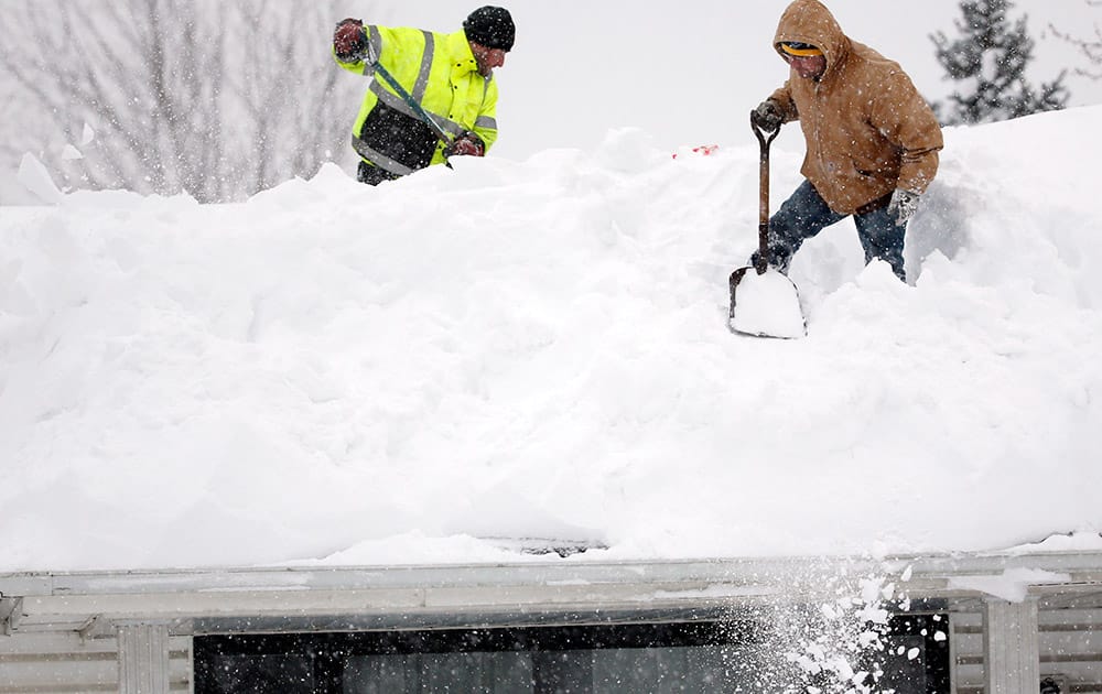 Mark Settlemyer, left, gets help clearing snow from the roof of his mother's house from Ken Wesley in Lancaster, New York.