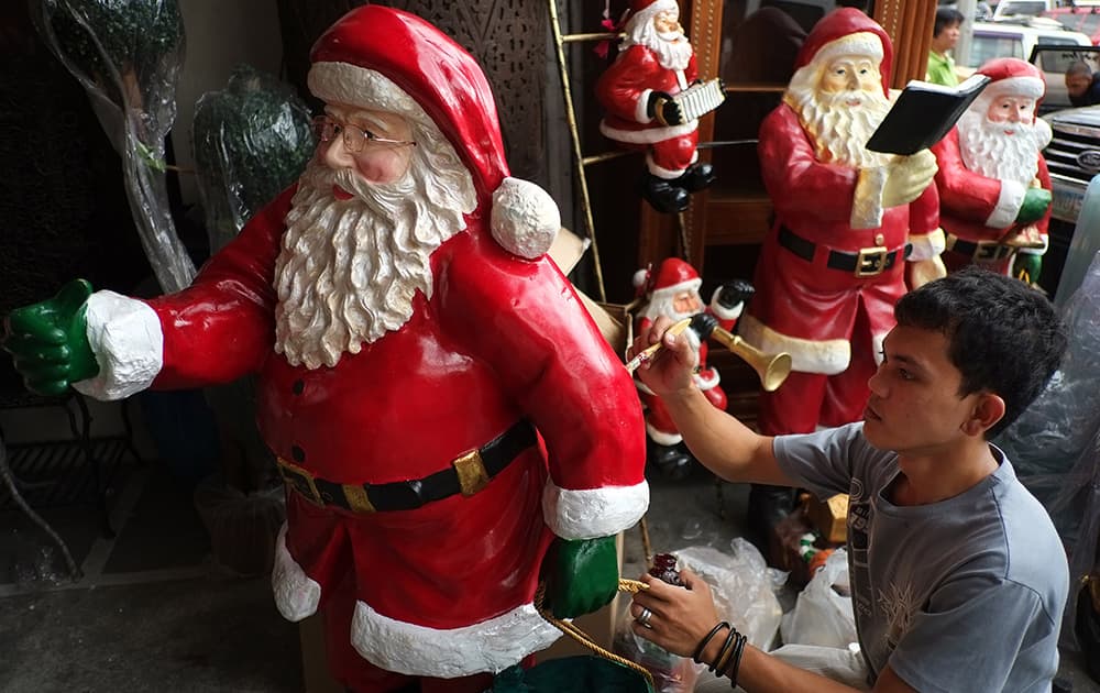 A Filipino man puts on finishing touches on a Santa Claus figure as people begin shopping for Christmas decorations in Manila, Philippines.
