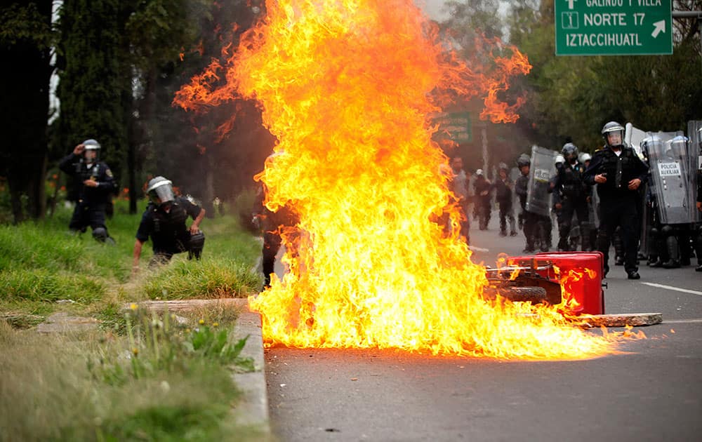 A motorcycle burns after protesters threw molotov cocktails at riot police near the airport in Mexico City.