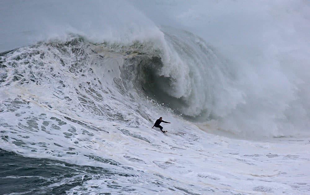 A surfer rides a big wave during a tow-in surfing session at the Praia do Norte or North beach, in Nazare, Portugal.