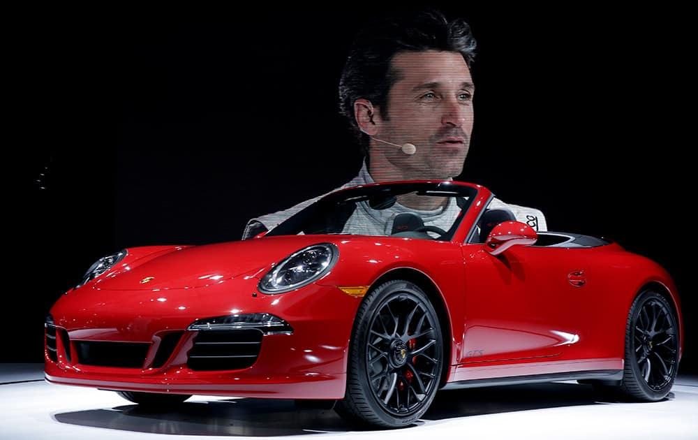 Actor Patrick Dempsey, is projected on a screen behind as he talks about the 2015 Porsche 911 Carrera GTS during the Los Angeles Auto Show, in Los Angeles.