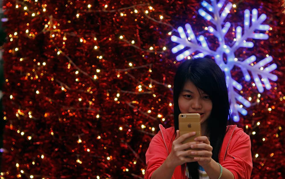 A shopper takes a selfie in front of Christmas decorations at a shopping mall in Kuala Lumpur, Malaysia.