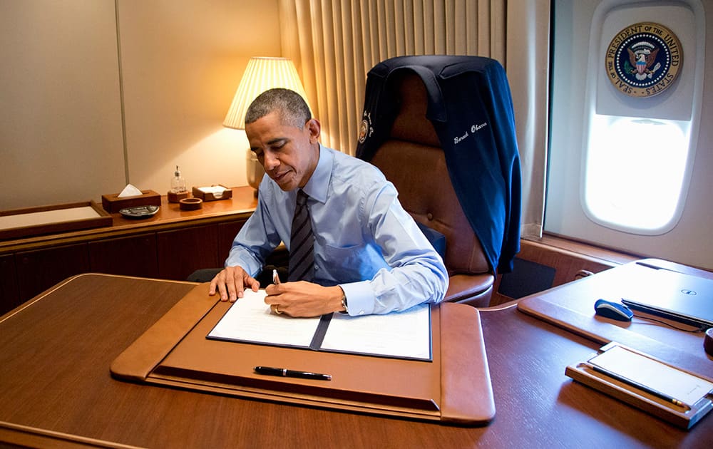 President Barack Obama signs two presidential memoranda associated with his actions on immigration in his office, on Air Force One as he arrives at McCarran International Airport in Las Vegas.