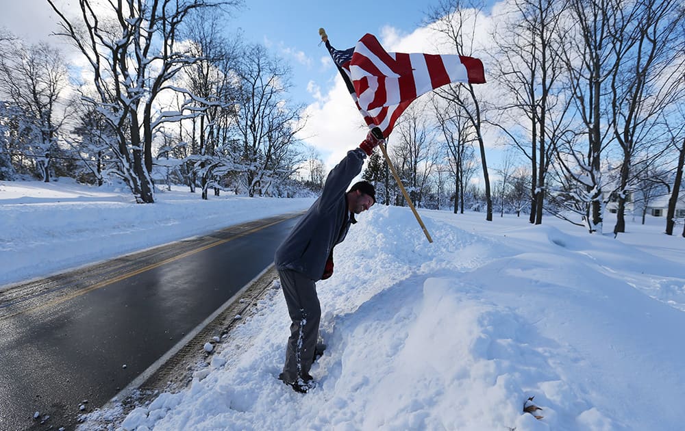 Jim Bammel stick an American flag in the snow bank in front of his house a signal to the person who plows his driveway at his home in Orchard Park, N.Y.