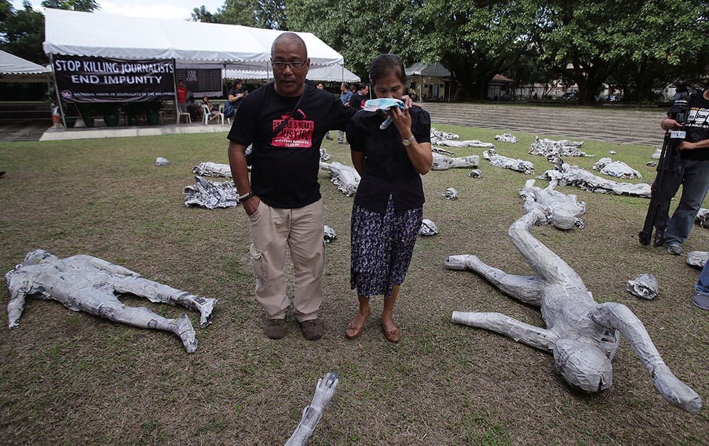 Edita Tiamzon, right, widow of slain journalist Daniel, breaks into tears as she views an art exhibit to mark the 5th anniversary of the massacre of 58 people, 32 of them journalists, in suburban Quezon city, north of Manila, Philippines.