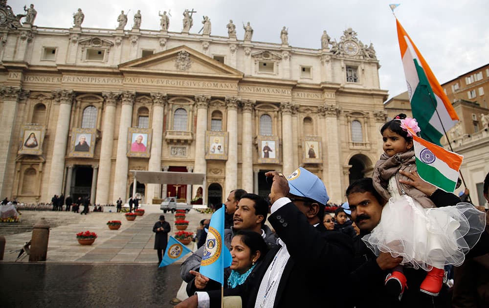 Faithfuls gather in front of St. Peter's Basilica, adorned with the tapestries, from left, of Eufrasia Eluvathingal, Amato Ronconi, Antonio Farina, Kuriakose Elias Chavara, Nicola Saggio da Longobardi and Amato Ronconi prior to the start of the Canonization Mass celebrated by Pope Francis in St. Peter's Square, at the Vatican.