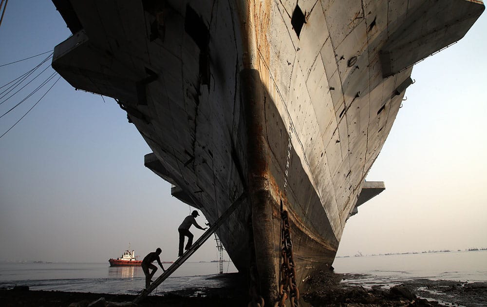 Workers climb to enter India's first aircraft carrier INS Vikrant to dismantle it at a ship-breaking yard in Mumbai, India.