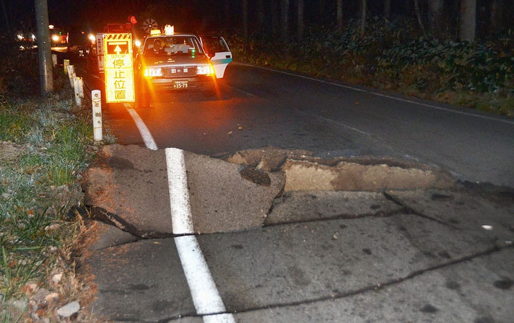 A taxi stops by a crack on the road that leads to Hakuba from Nagano, Nagano Prefecture, after a strong earthquake hit central Japan.
