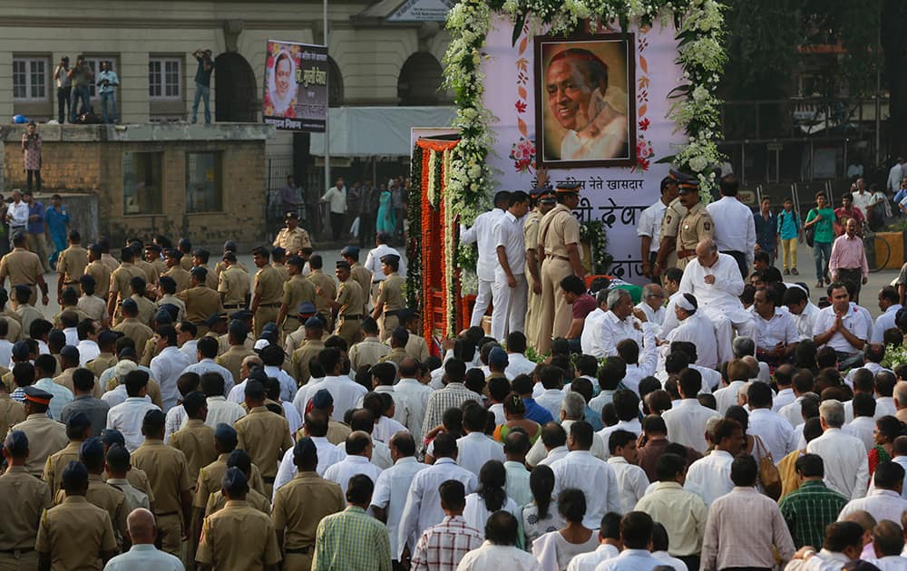 People and policemen walk along as the body of former Indian minister Murli Deora is taken for cremation in Mumbai.