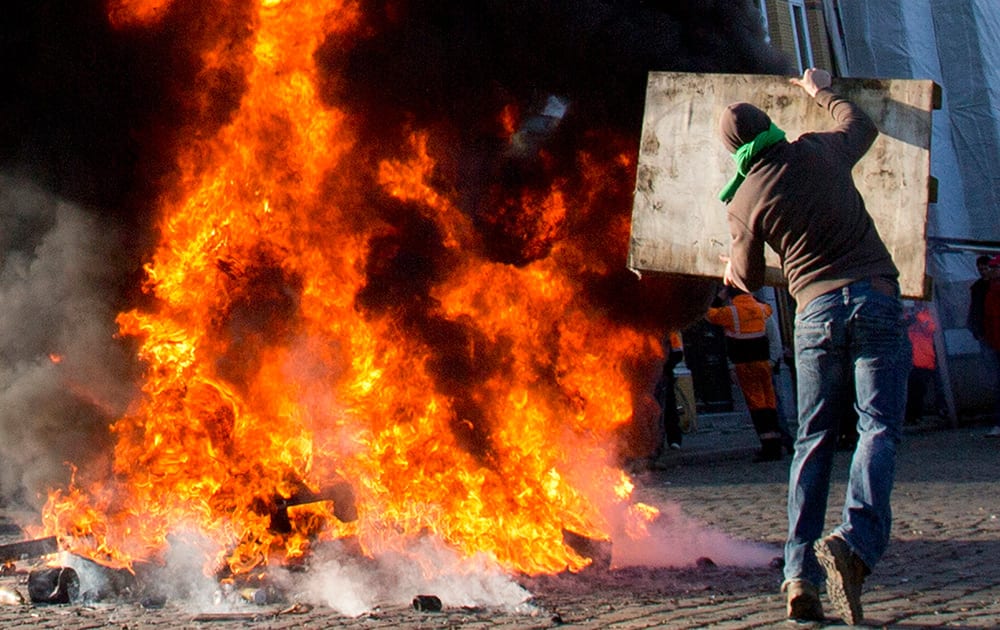 A man throws a wooden pallet onto a fire during a demonstration in the Port of Antwerp in Antwerp, Belgium. Trade unions opened a month of intermittent strike actions by paralyzing the port of Antwerp and slowing train traffic through much of Belgium. 