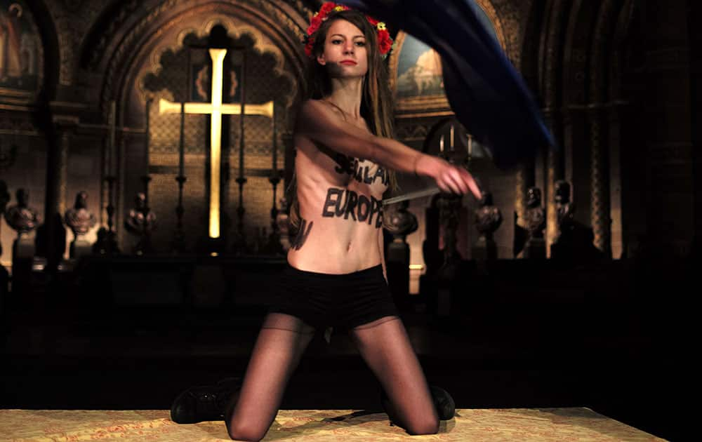 A member of the Ukrainian feminist protest group FEMEN, waves the European Union flag, as she stages a protest inside the cathedral of Strasbourg, eastern France.