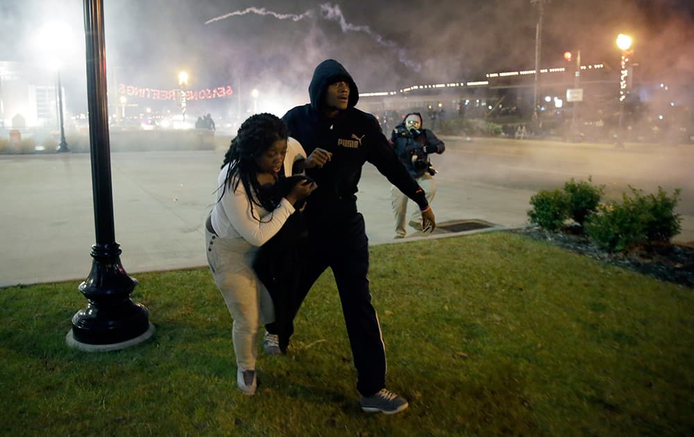 Protesters run for shelter as smoke fills the streets after the announcement of the grand jury decision not to indict police officer Darren Wilson in the fatal shooting of Michael Brown, in Ferguson, 