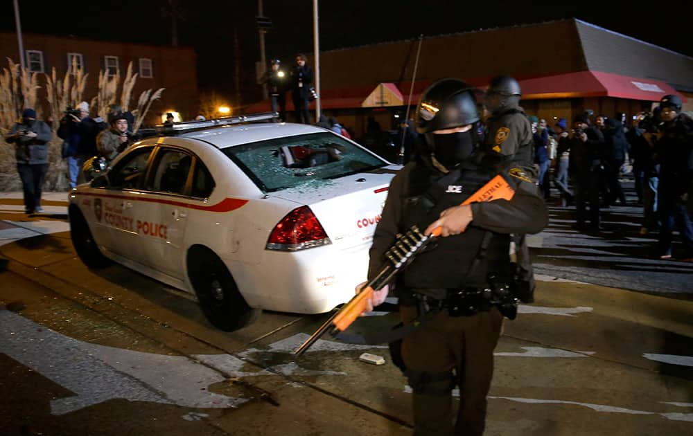 An armed police officer guards the area after a group of protesters vandalize a police cruiser after the announcement of the grand jury decision not to indict police officer Darren Wilson in the fatal shooting of Michael Brown, in Ferguson.