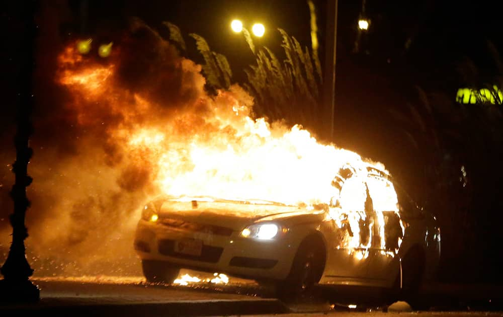 A police car is set on fire after a group of protesters vandalize the vehicle after the announcement of the grand jury decision, in Ferguson.