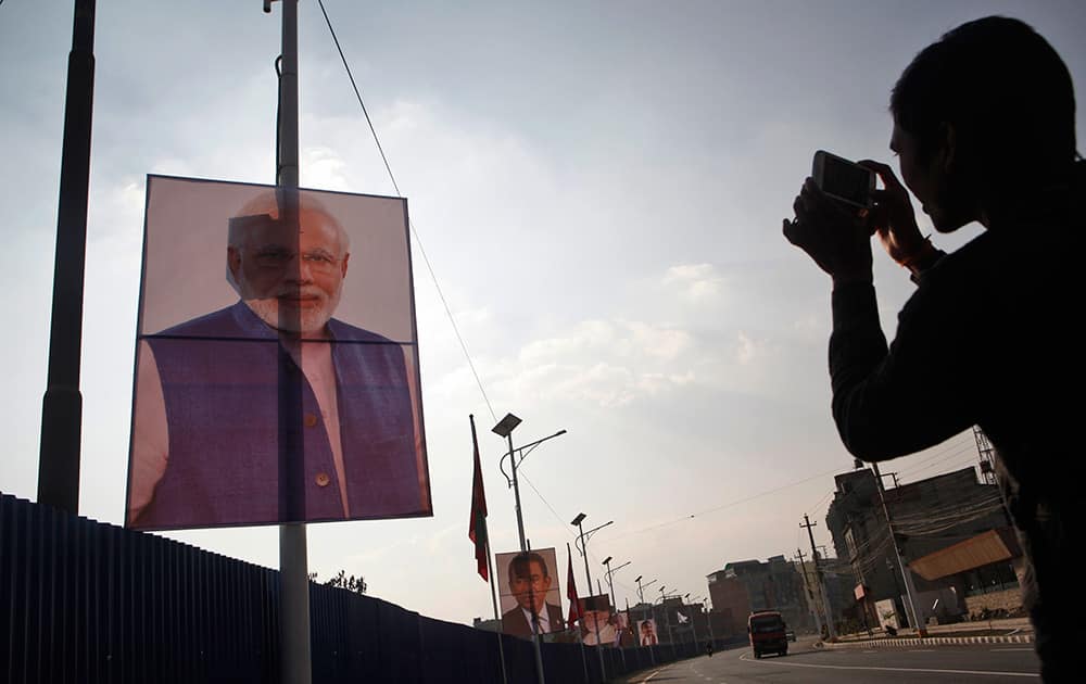 A Nepalese man photographs a portrait of Indian Prime Minister Narendra Modi displayed on a road side along with other heads of South Asian Association for Regional Cooperation (SAARC), countries in Katmandu, Nepal.