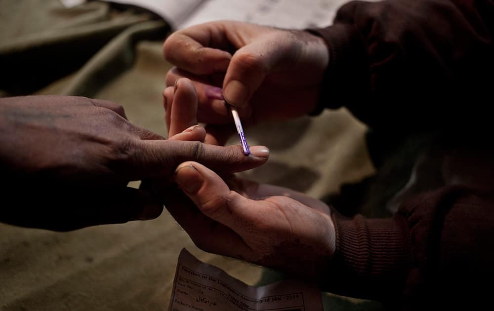 A polling officer, puts an ink mark on the finger of a voter during the first phase of voting to the Jammu and Kashmir state assembly elections in Khranihama, some 25 kilometers (16 miles) north east of Srinagar.