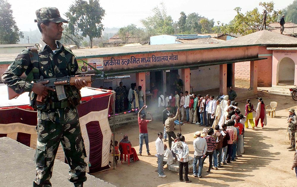 A security person stands guard outside a polling station during the first phase of Jharkhand assembly election in Latehar.