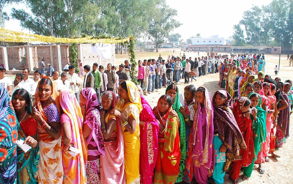 Voters wait to cast their votes at a polling station during the first phase of Jharkhand assembly election, in Latehar.