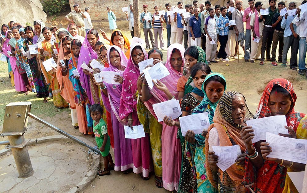 Women display their identity cards while waiting to cast their vote during the first phase of Assembly elections in Chatra district of Jharkhand.