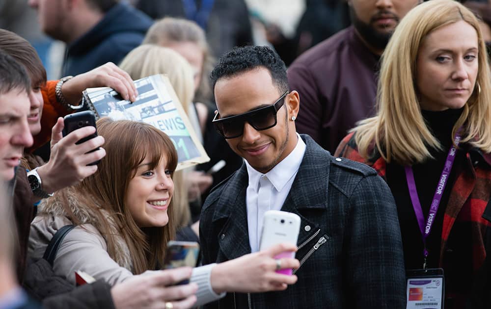 Britain's 2014 F1 Racing World Champion Lewis Hamilton poses for photographs with members of the public after a visit to the MediaCityUk television and radio studios in Manchester, England.